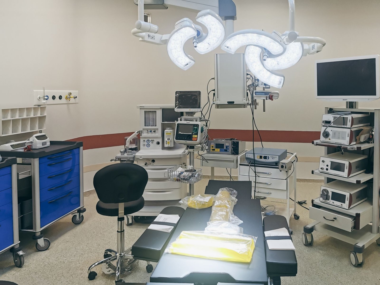 An empty, fully equipped modern operating room with surgical lights and monitoring equipment